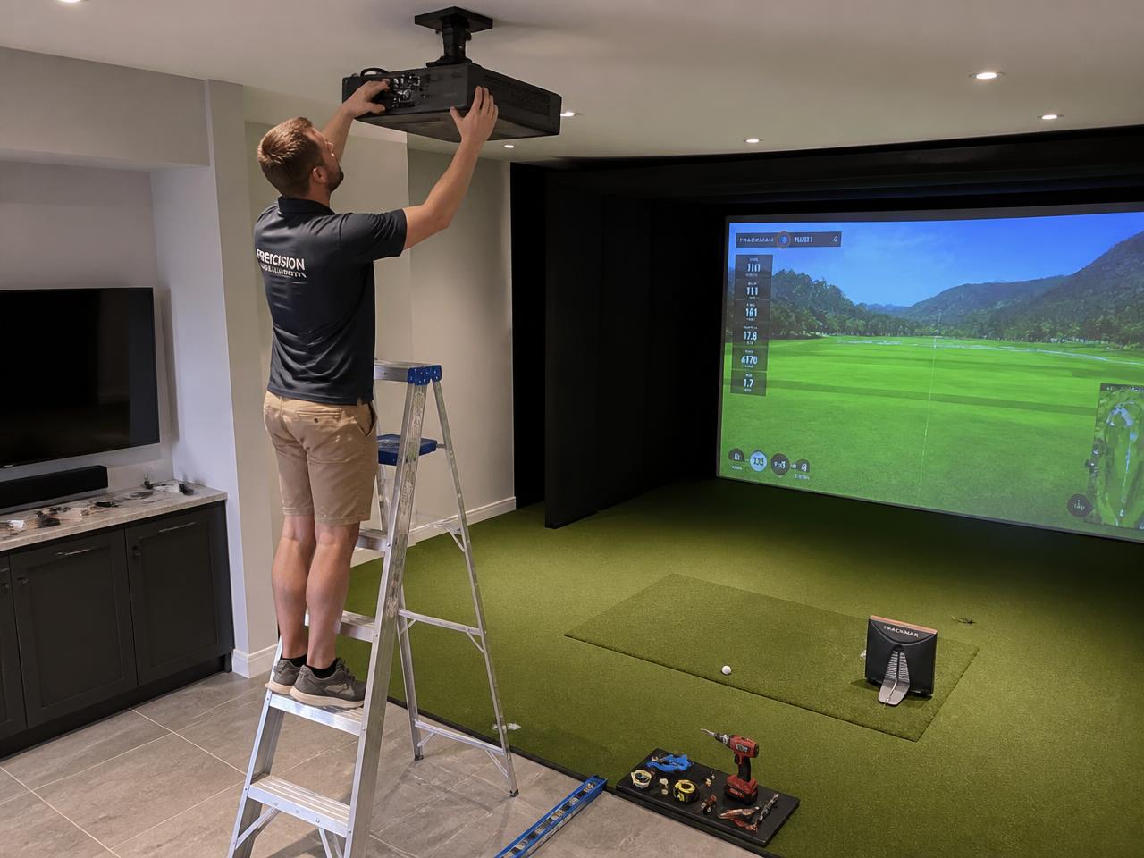 Installer mounting a projector in a golf simulator room